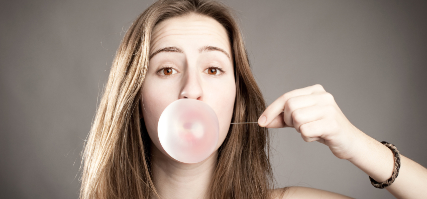 young woman making a bubble from a chewing gum